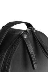 Close-up of a black leather bag with a visible brand tag on a white background