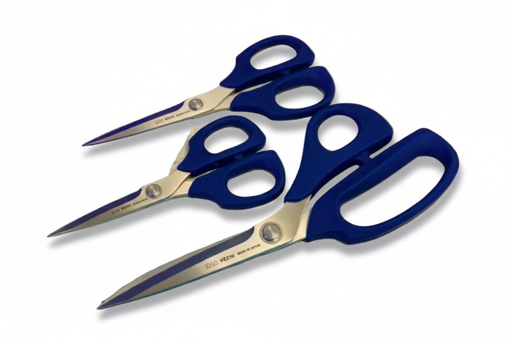 three pairs of blue-handled scissors on a colorful fabric background with visible model numbers.