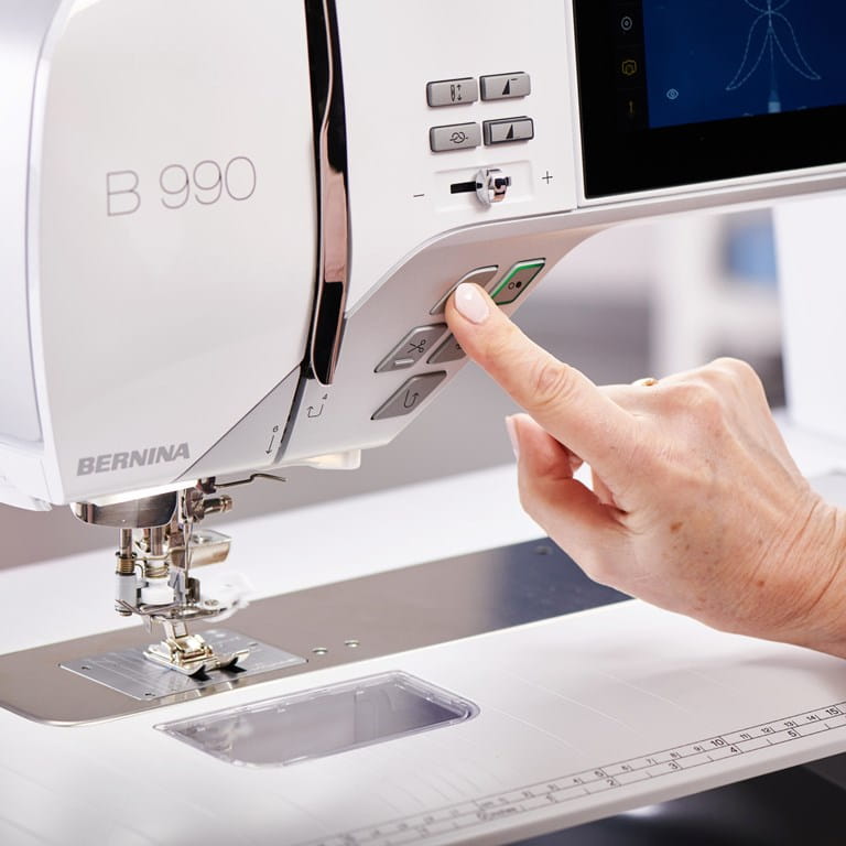 Close up image of a person pressing a button on the Bernina 990 Sewing Machine.