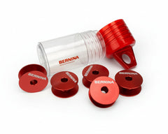 Red Bernina spools of thread with a clear container on a white background