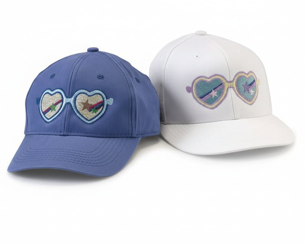 Two baseball caps with heart-shaped sunglasses designs on a white background