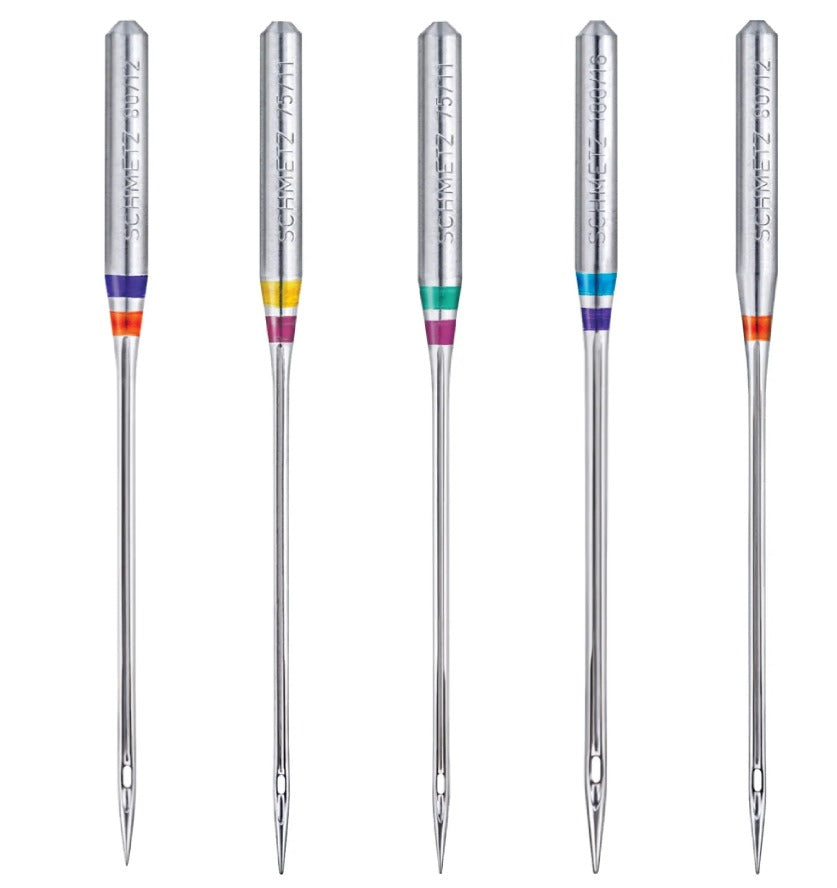 five domestic schmetz brand needles in a line, showing colour coding markings.